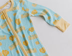 A baby long-sleeve zip-up sleeper in light blue with a gingham pattern and yellow butter-themed print, featuring yellow cuffs and a yellow zipper.