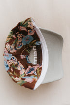 A baseball cap with a brown floral patterned back and a light gray visor, photographed on a white background.
