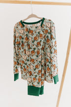 Two piece set of kid's pajamas with a duck and geese pattern hanging from a clothing rack with a plain white studio background.